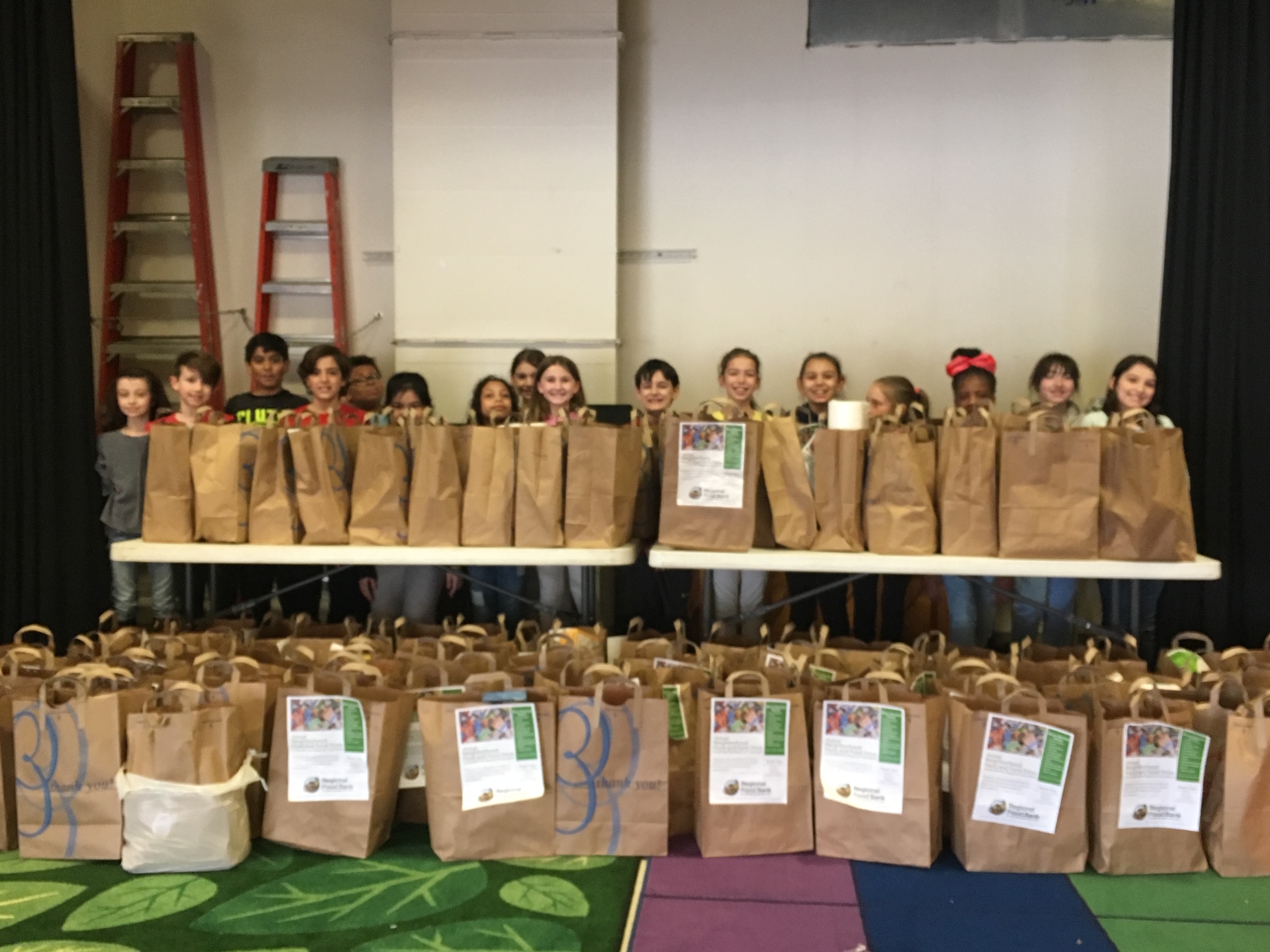 students stand with bags of collected items for food bank