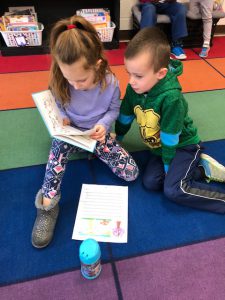 boy and girl read together on the floor