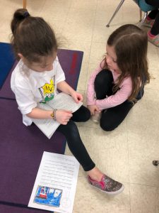 two girls read together on the floor