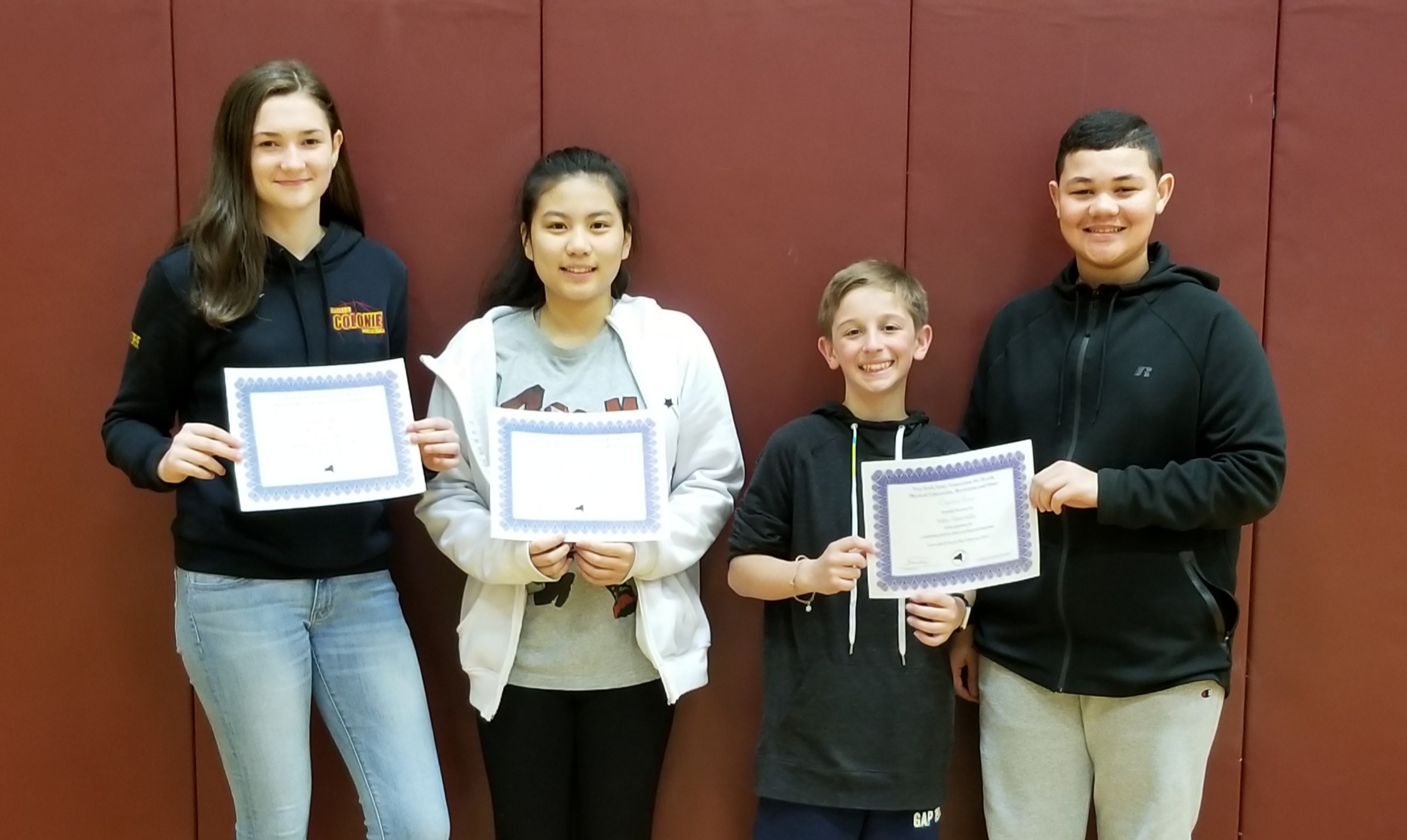 four students hold their award certificates