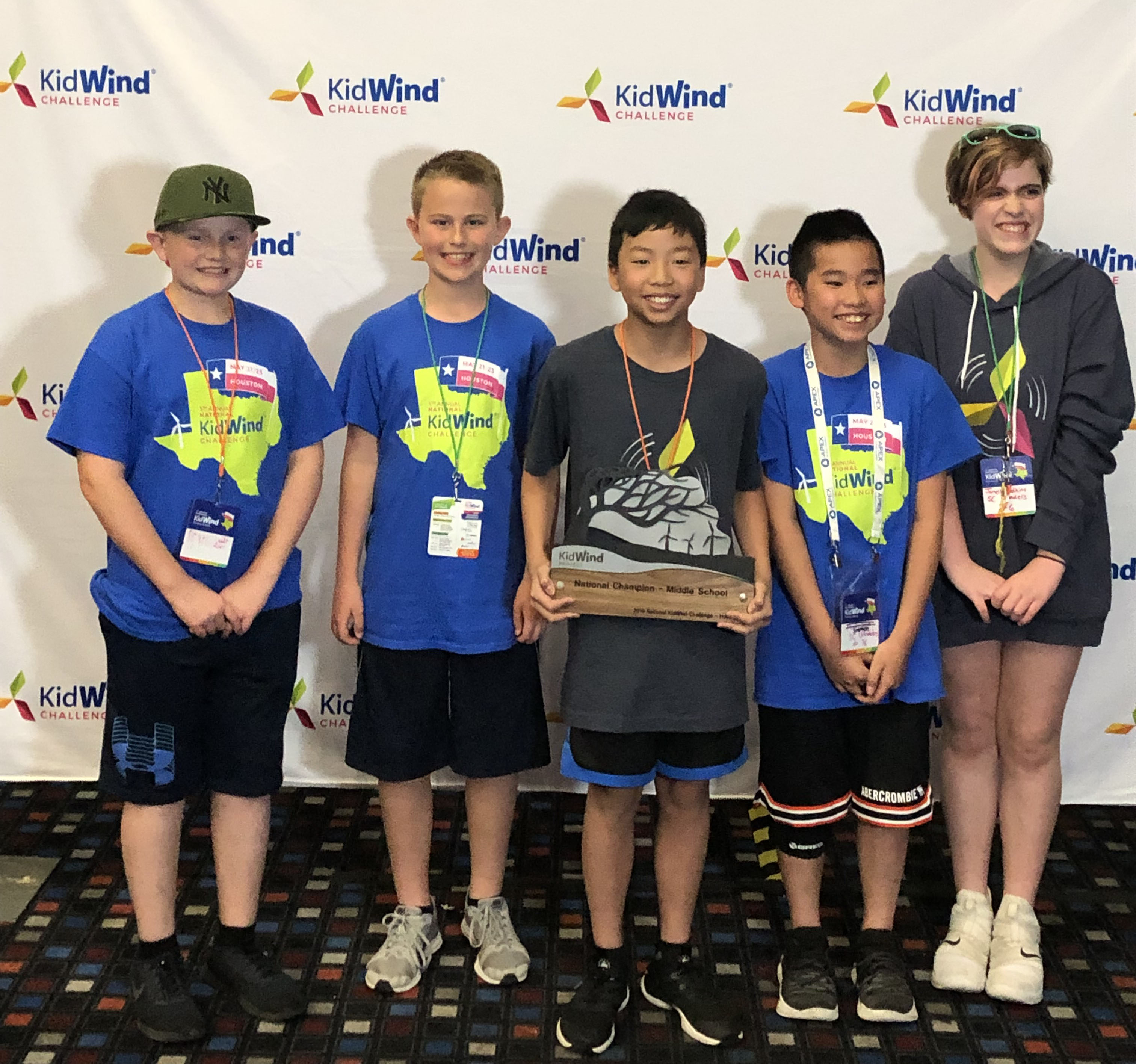 group of student in blue t shirt holding a trophy