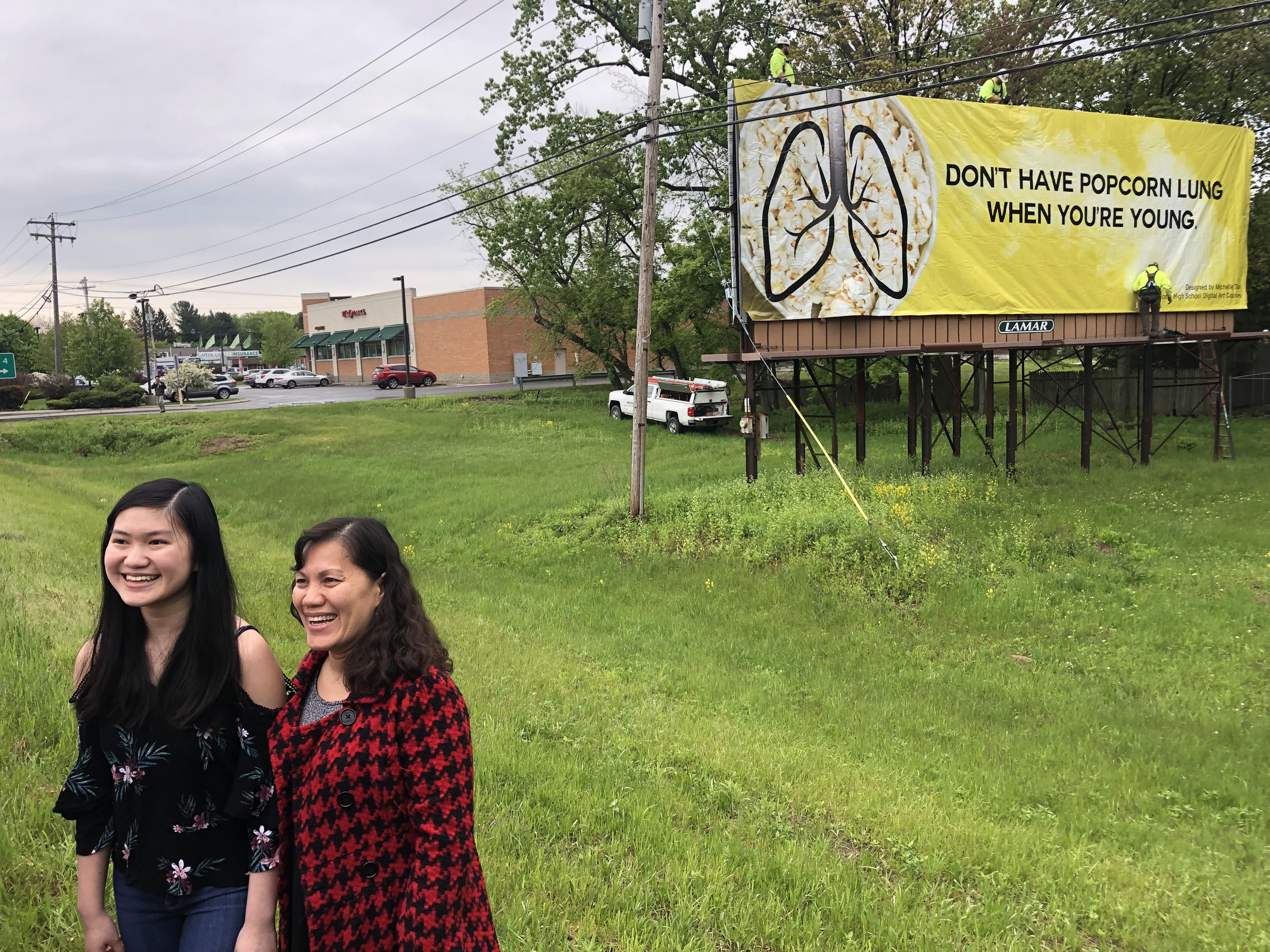 student and her mom stand in front of winning billboard design