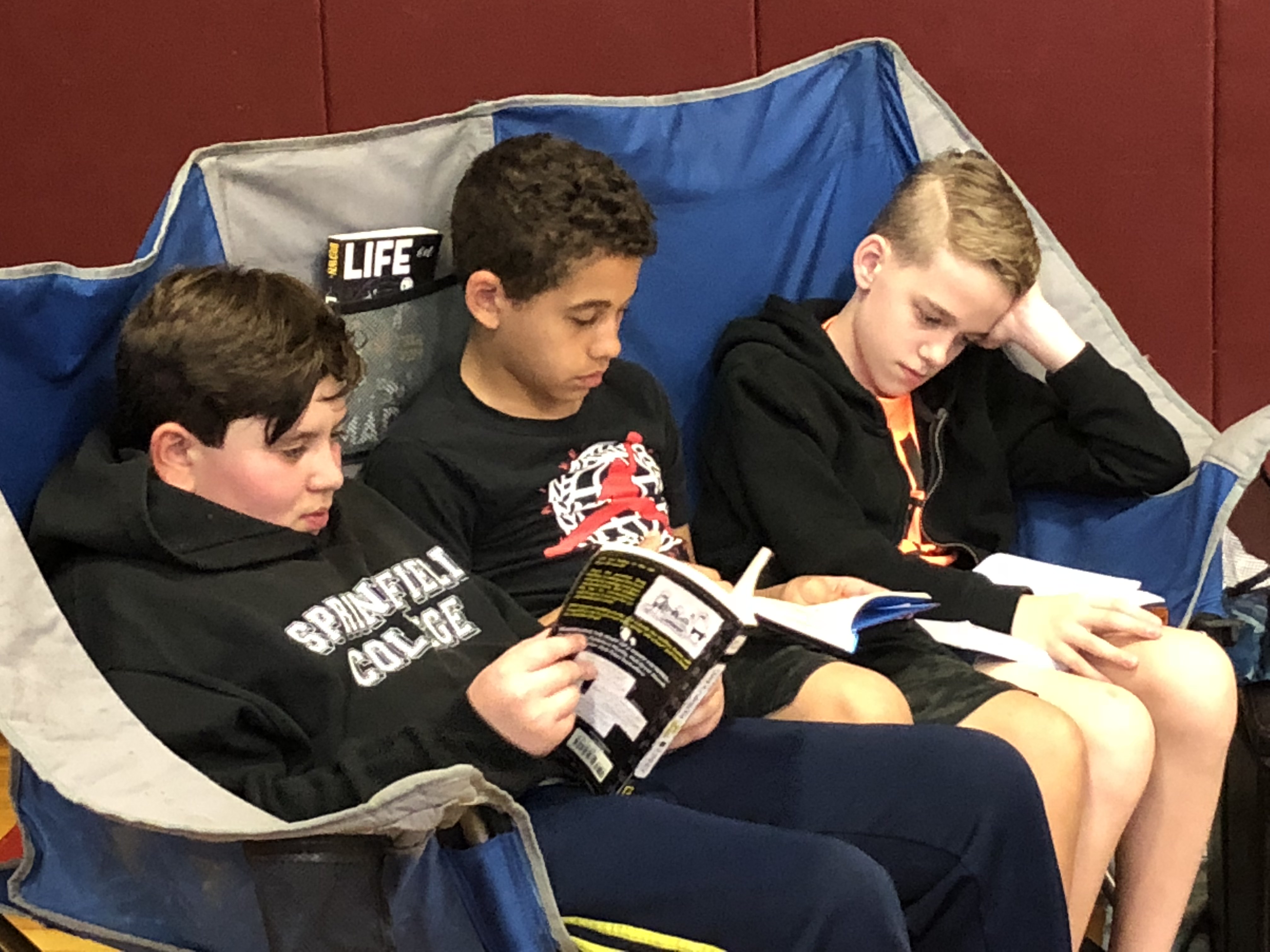 3 boys reading in a big chair