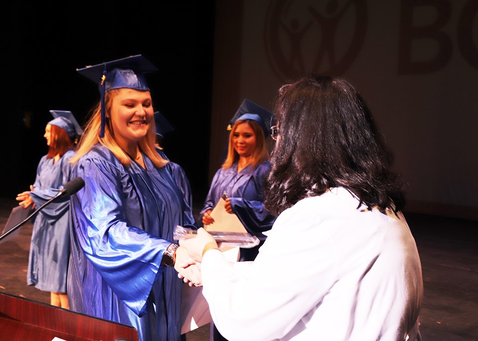 girl receives her diploma dressed in cap and gown