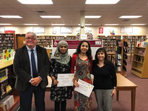 two girls stand with board members