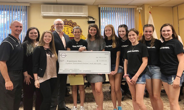 group of administrators and high school students pose with a big check