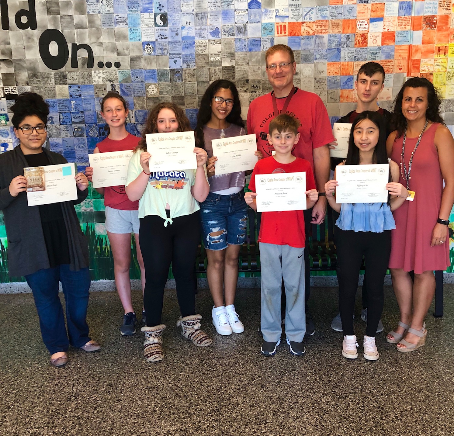 middle school students show off their award certificates