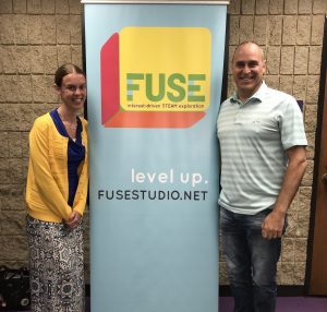 a man and a woman stand in front of a fuse poster