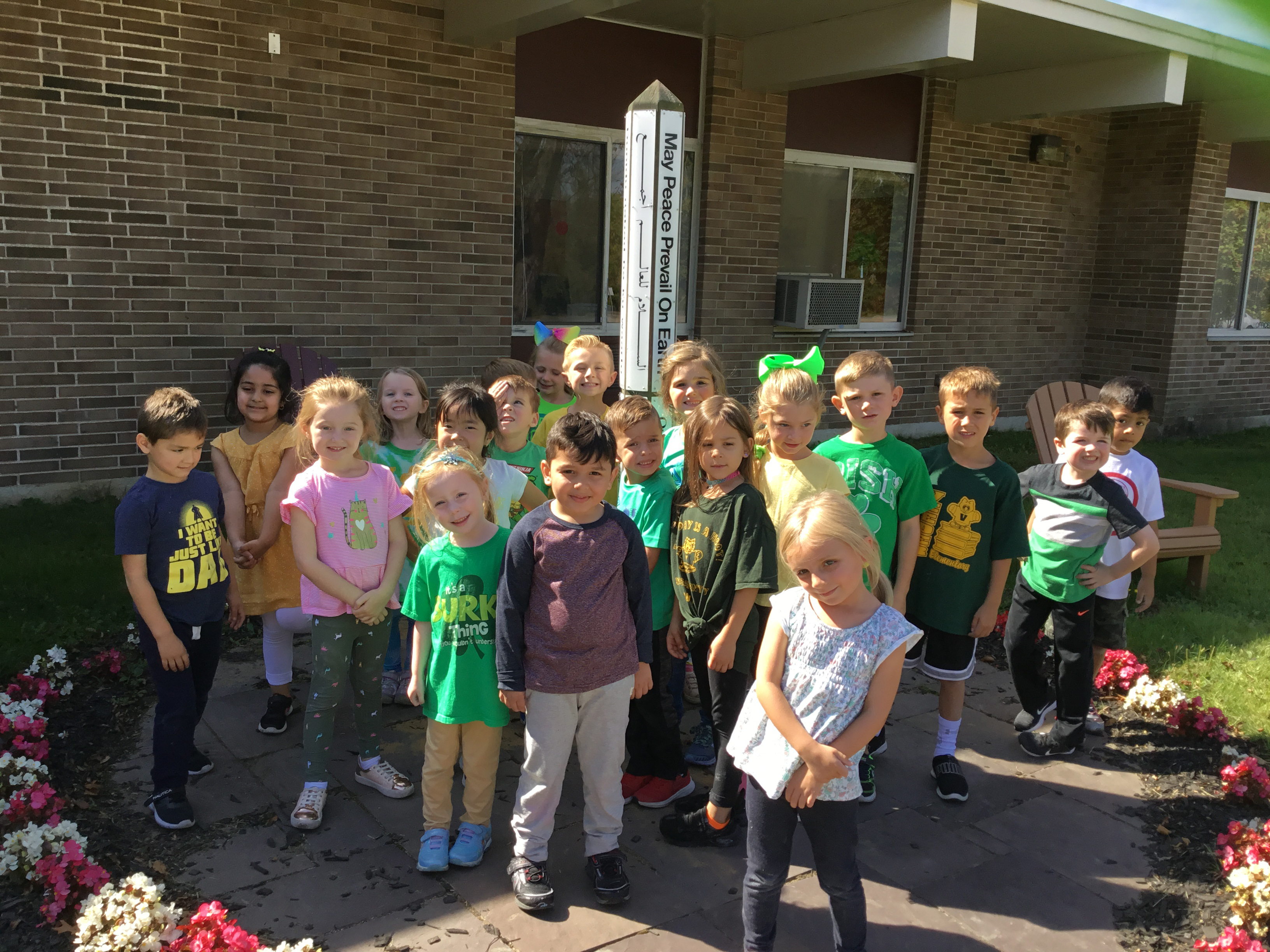 group of kindergartners stand in front of the school peach pole