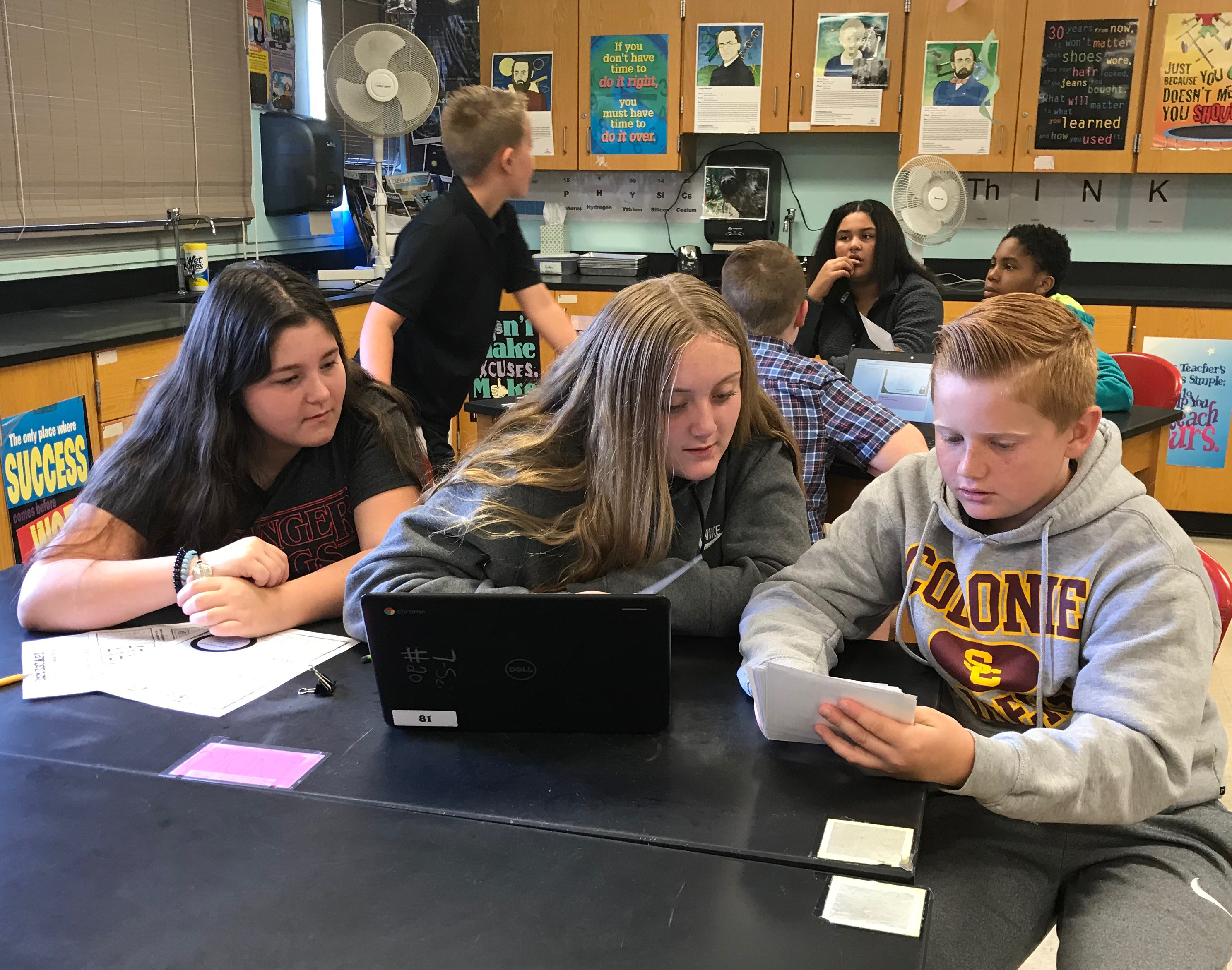 3 students work at a laptop together