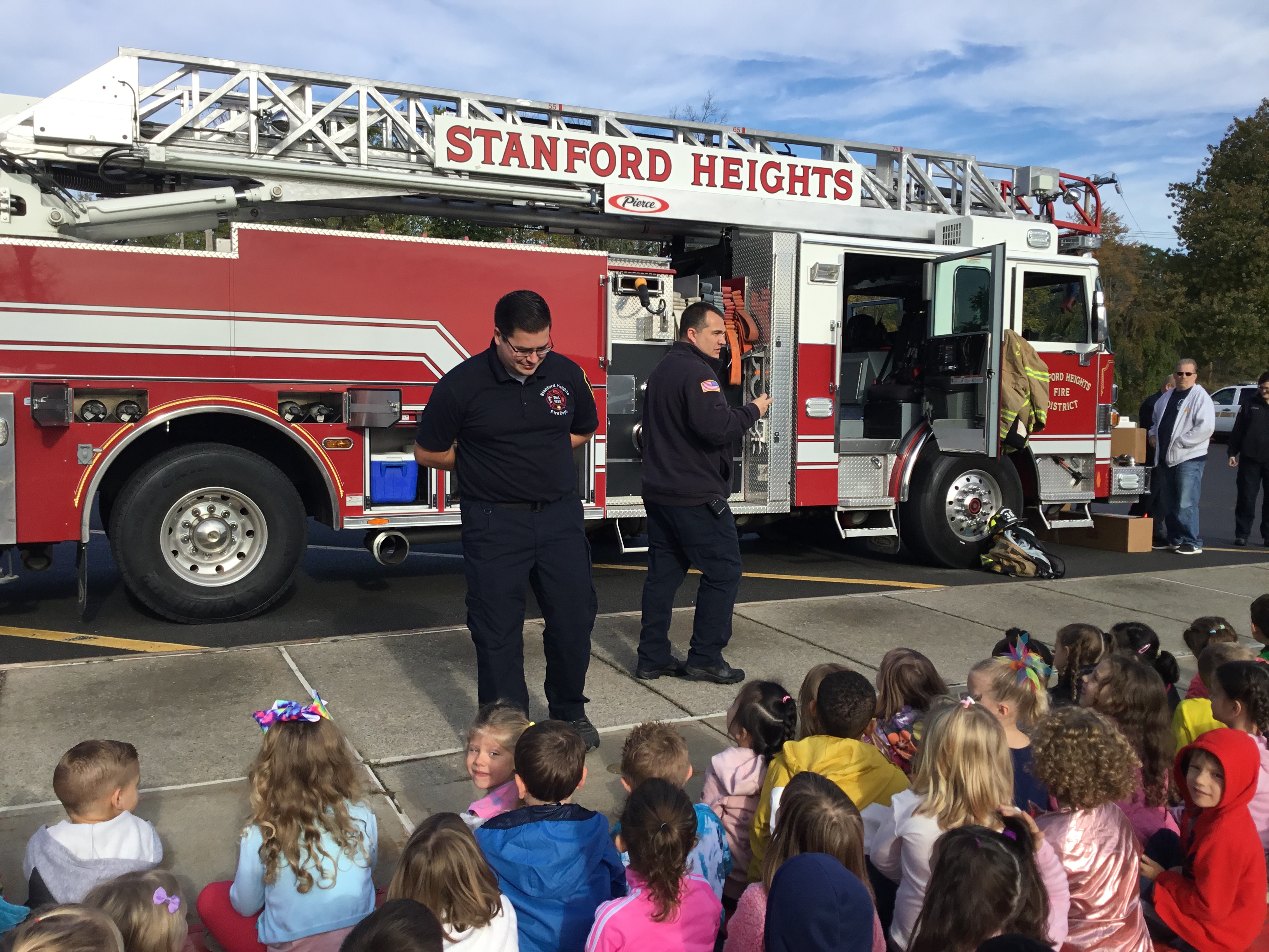 firefighters talk to students in front of big fire truck