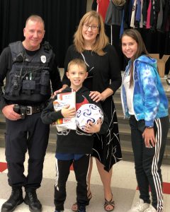 boy with soccer ball, police officer and other adults