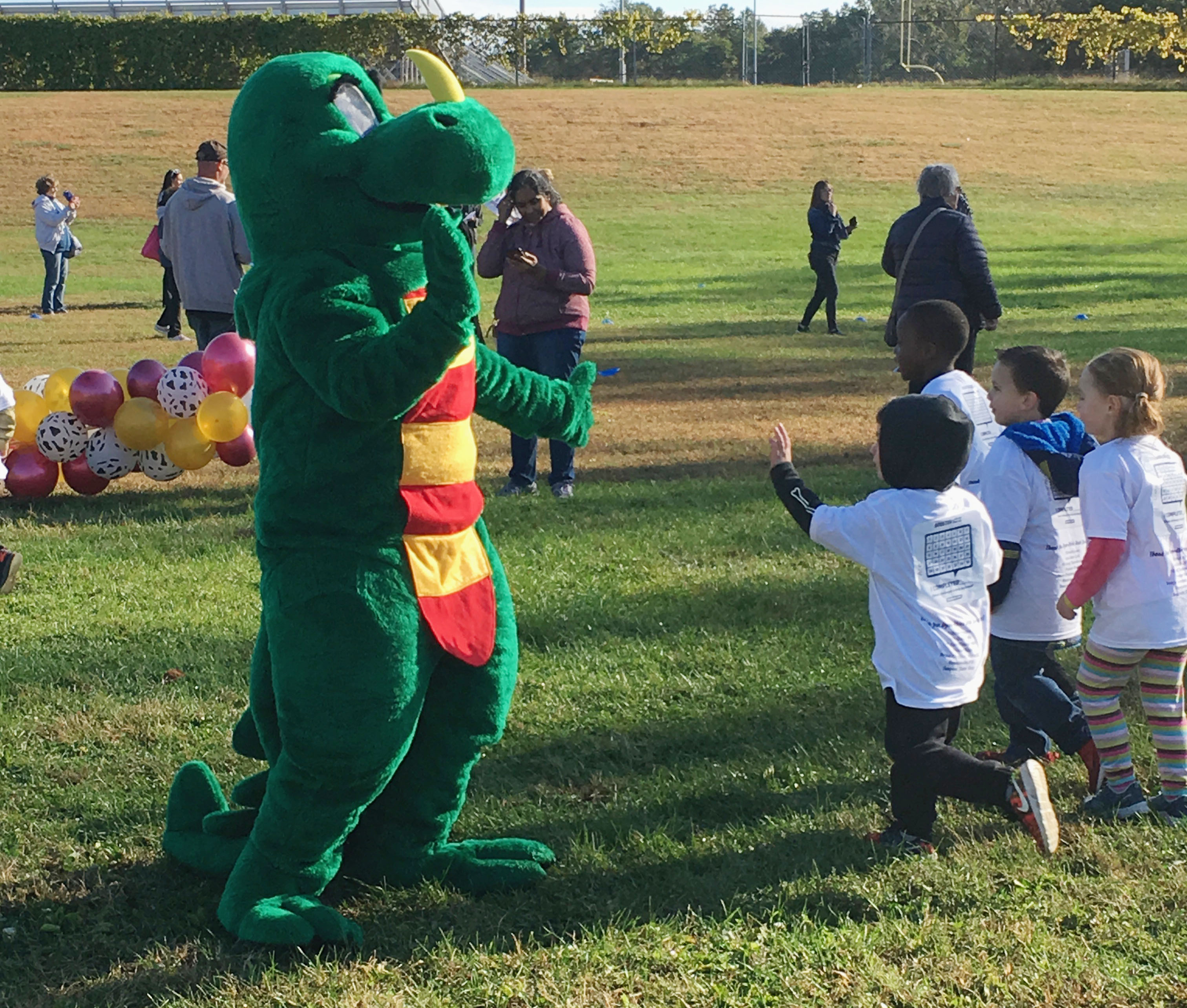 dinosaur gives high five to student runners