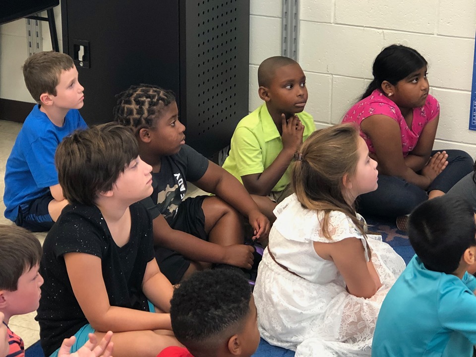 children listen to story on classroom floor