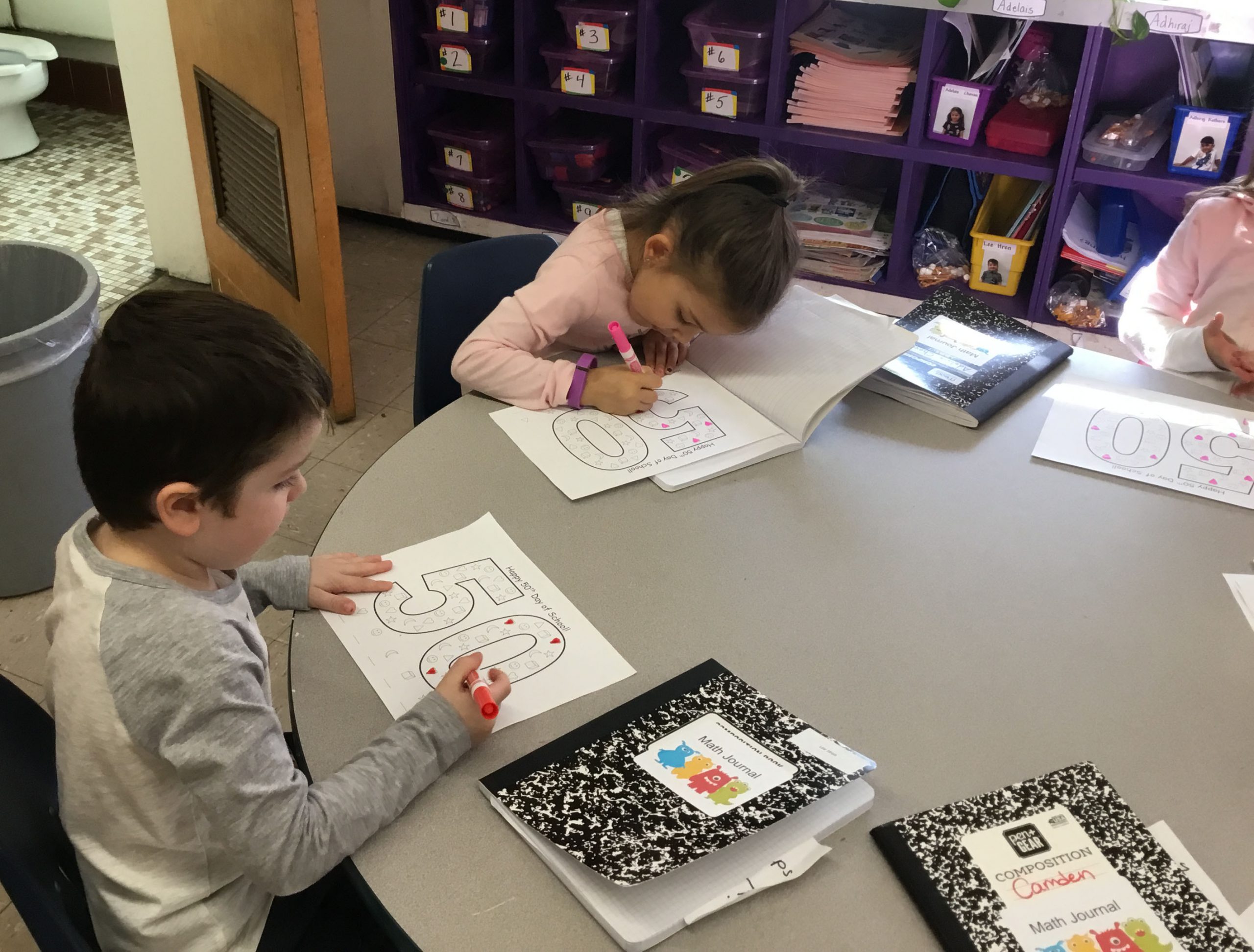 two children draw together at a table