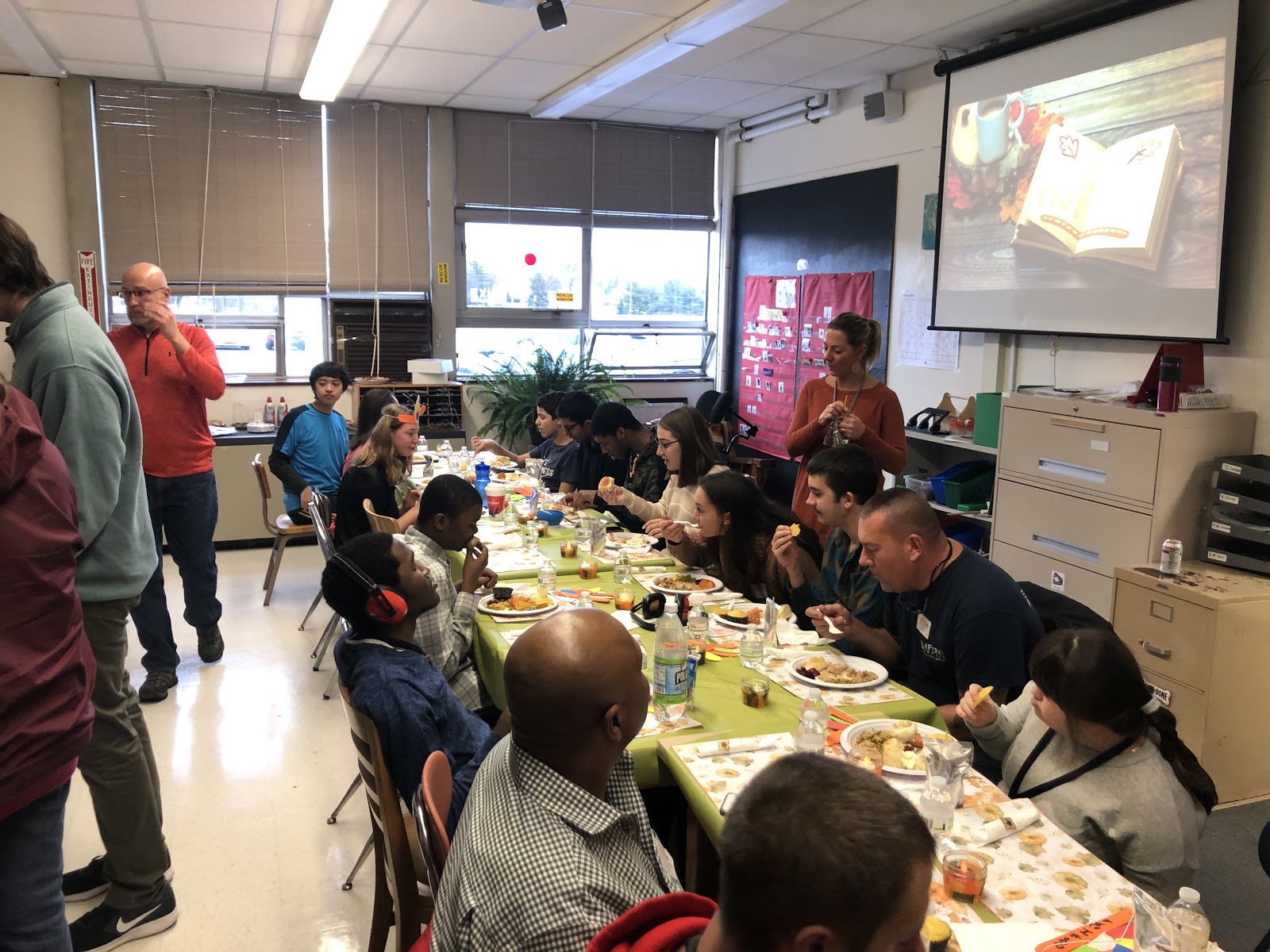 staff and students enjoy Thanksgiving dinner together at large table