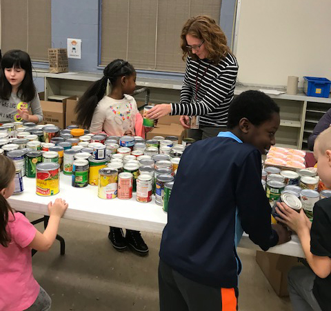 students and staff sort canned goods on a large table