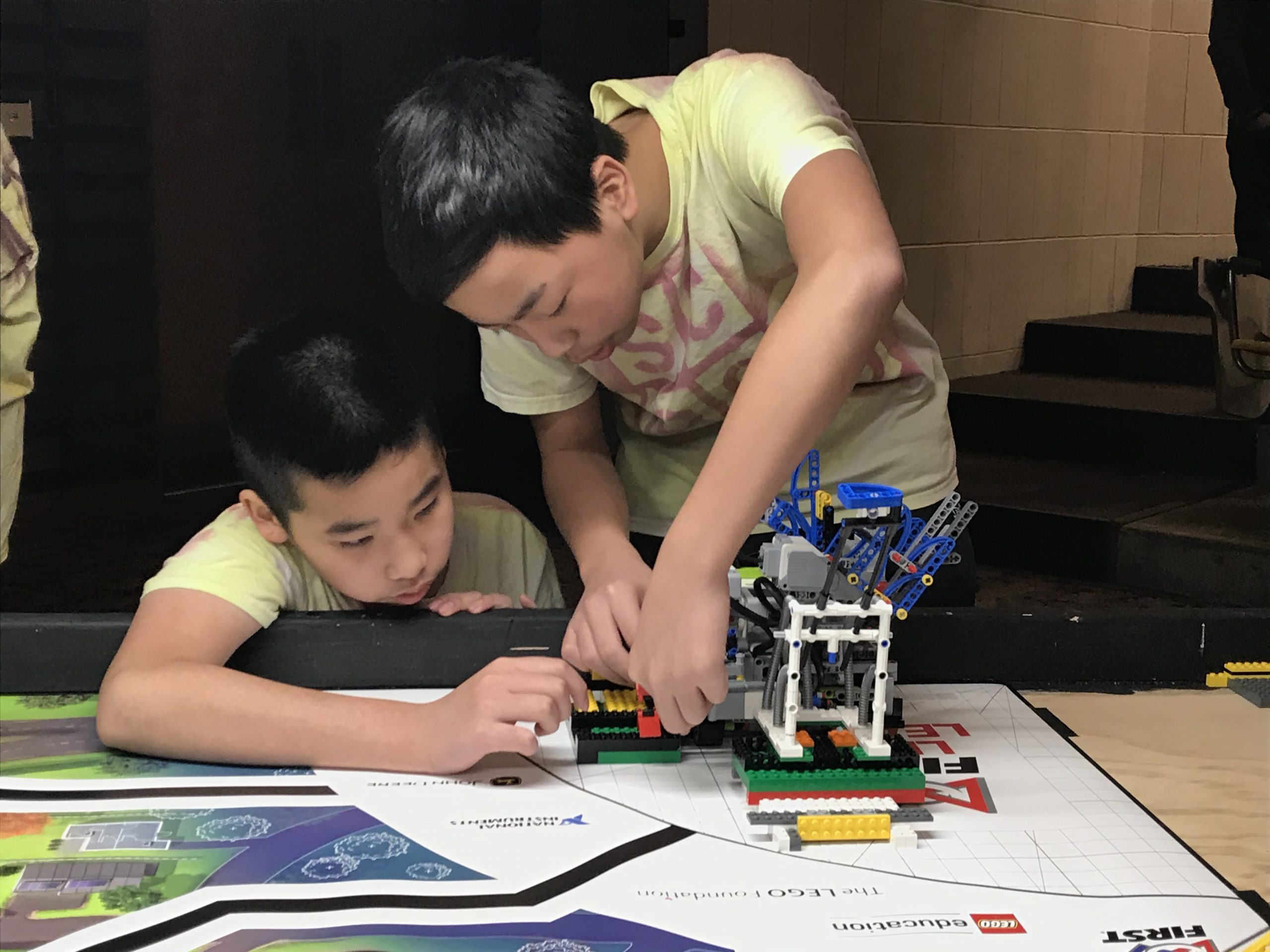 two boys work on a robot together