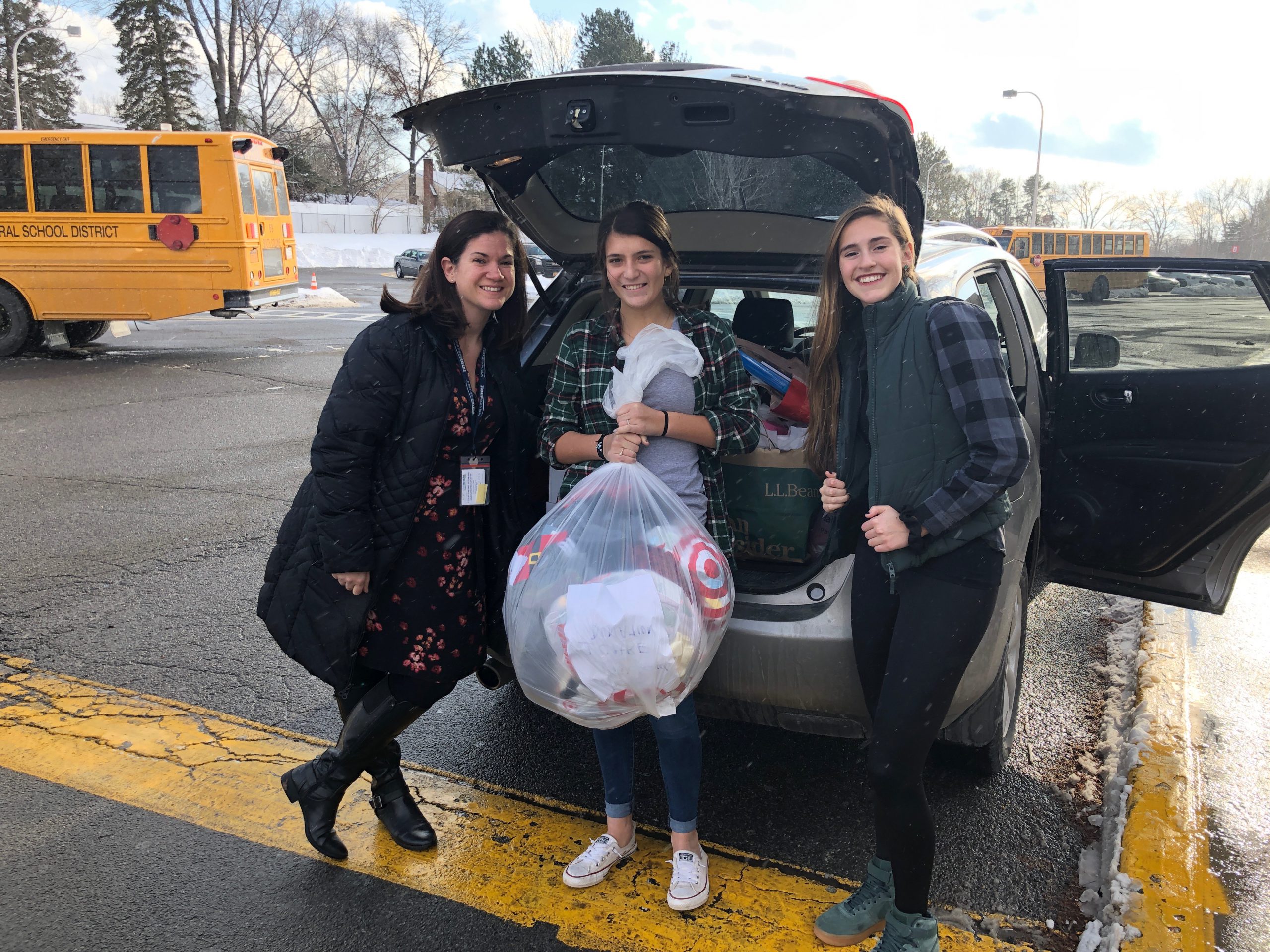 three students load bags of clothes into van