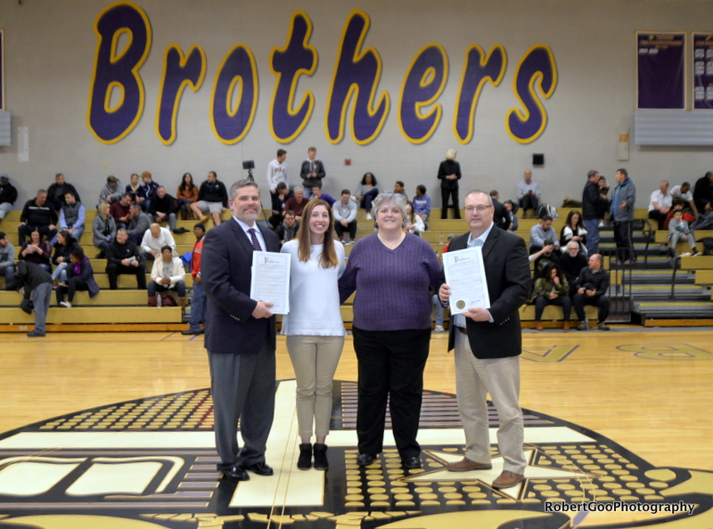 four people stand at half court with proclamations in hand