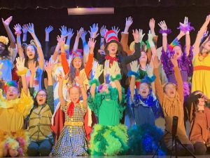 students in costumes on stage.