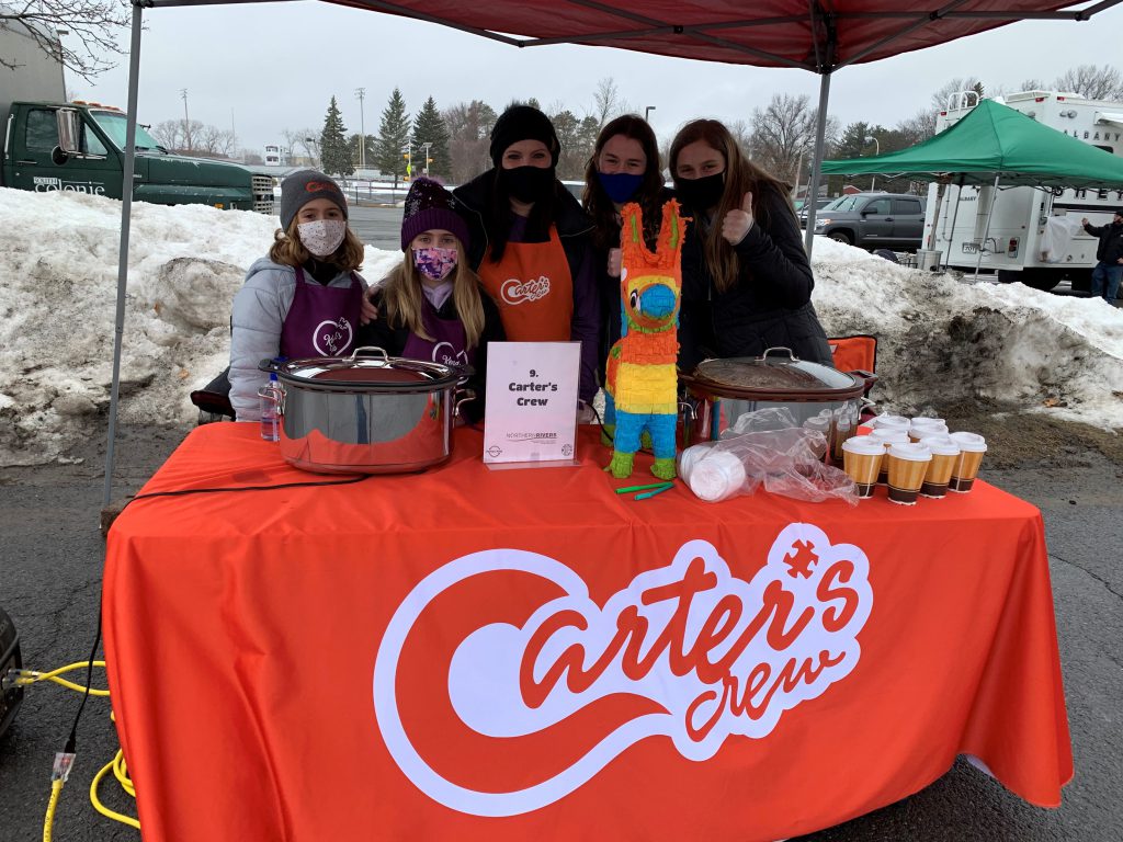 group of people showing off their chili at a chili cookoff outside