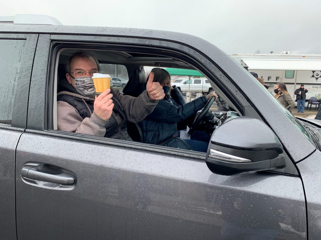 two people in a car showing off their cups of chili