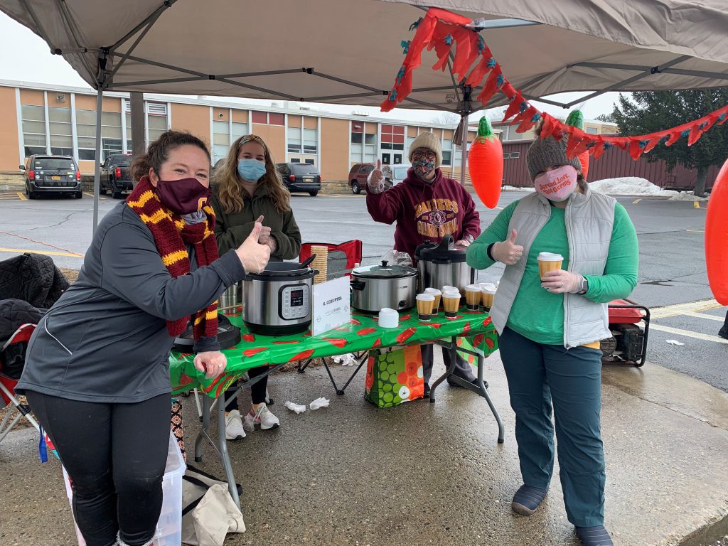 a group of people showing off their chili and decorated booth at a chili cookoff outside