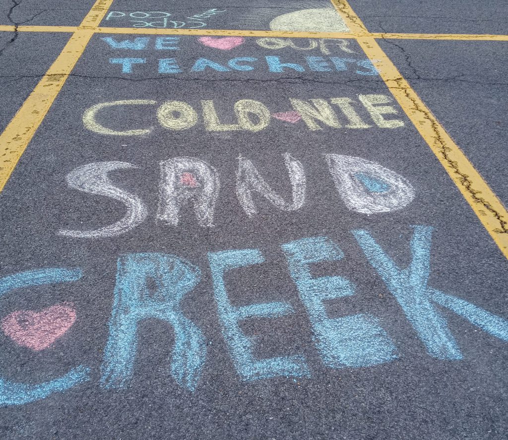 Picture of a sidewalk art that says  "We love our teachers. Colonie. Sand Creek"