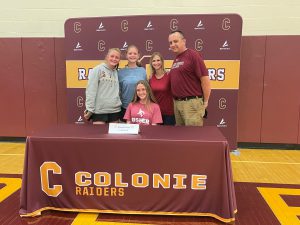 student posing with her family in front of a Colonie raiders backdrop.