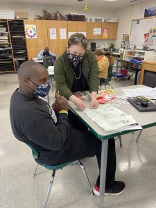 teacher works with student in classroom