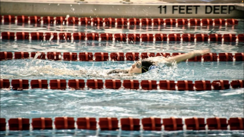 student swimming in the pool doing the backstroke.