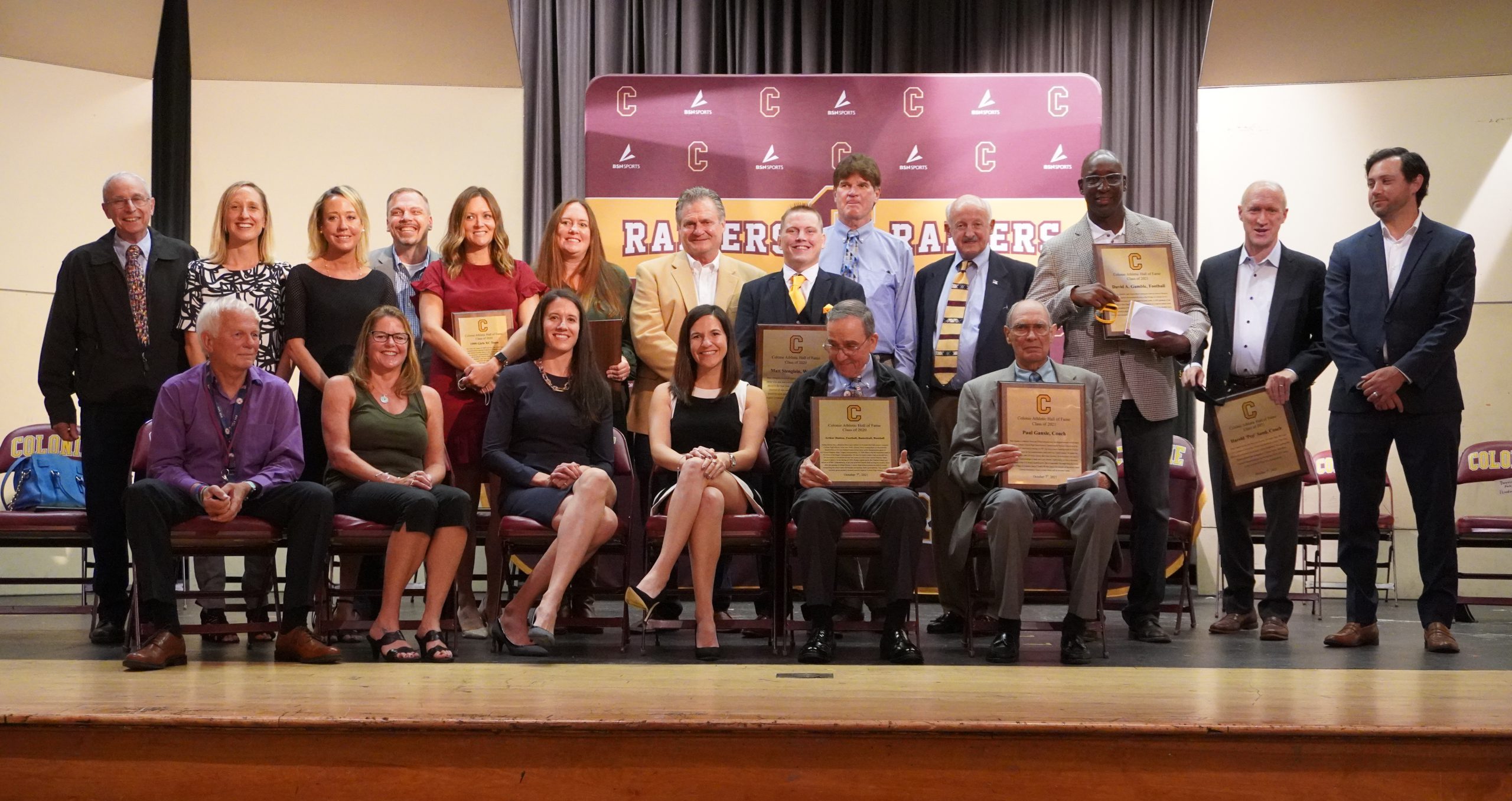 A group of people standing on a stage holding individual plaques.