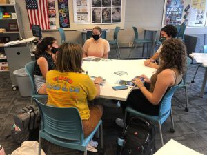 a group of students gather around a table in a career counseling center at a high school.