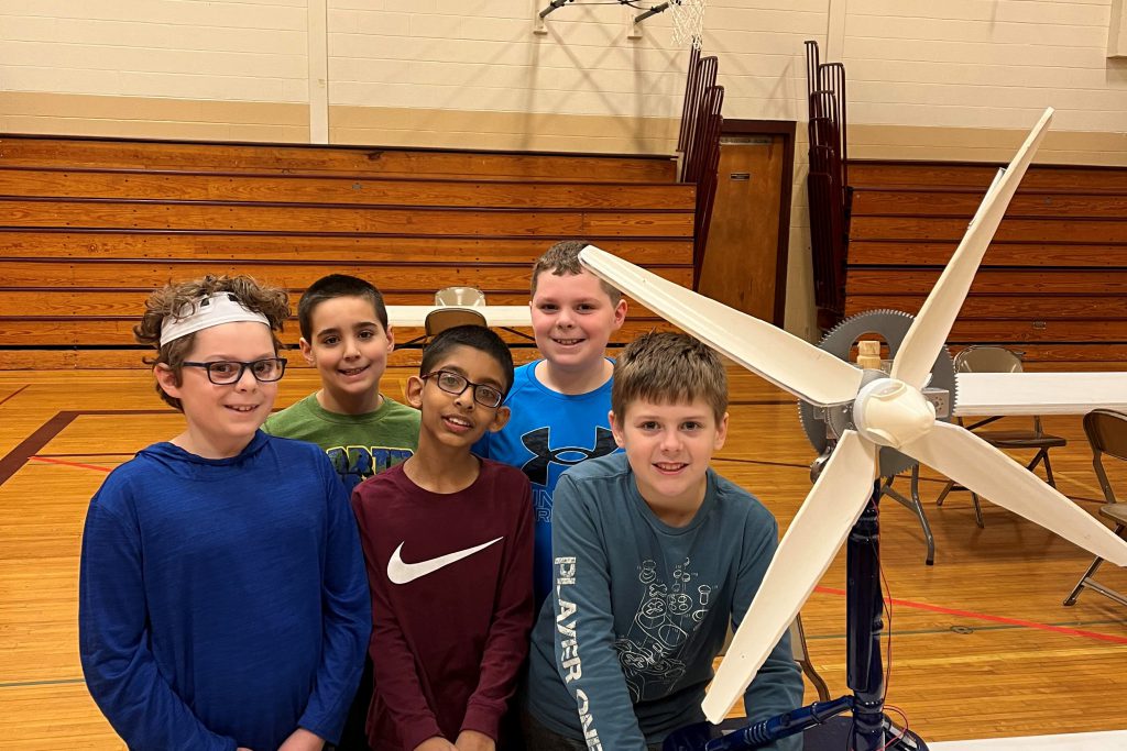 students posing with a hand made wind turbine