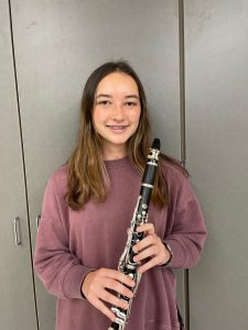 student posing for a photo while holding her clarinet. 