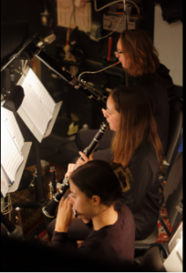 three students together playing orchestra instruments. 