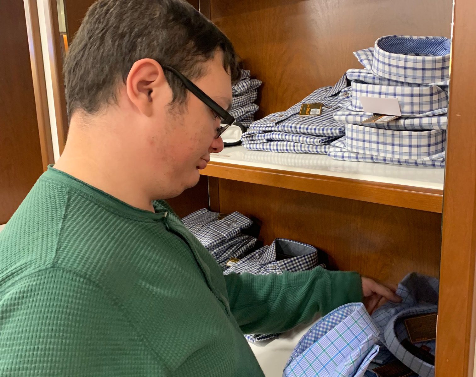 a student holds a folded shirt in a department store