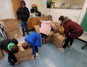 students work together to pack boxes of food. 