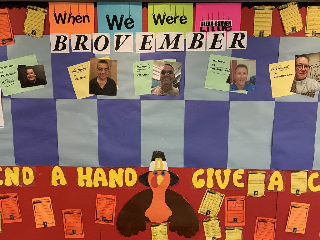 decorated bulletin board displaying staff faces of those participating in BROvember.