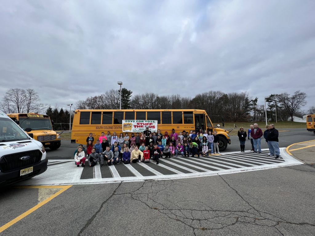 staff and students pose outside of the bus after stuffing it full of toys