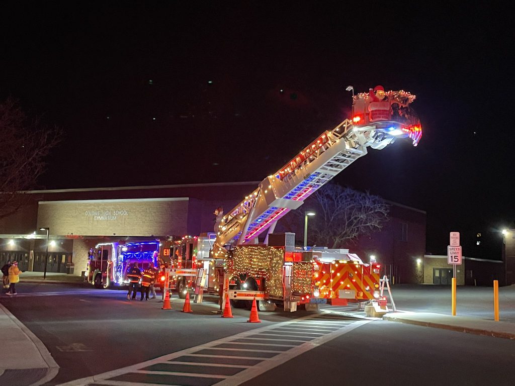 photo of a fire truck light up with lights. in front of the high school. 