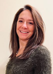 A staff member with straight brown hair smiling at the camera.