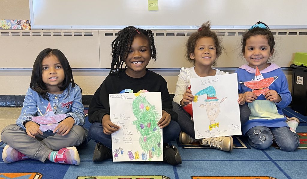 four students proudly show off their artwork.