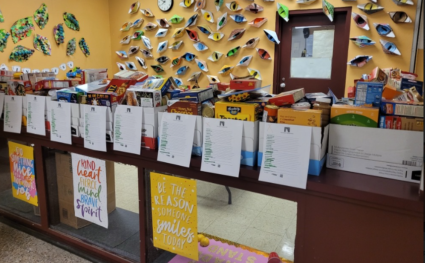 Boxes of food lined up on a table inside a school. 