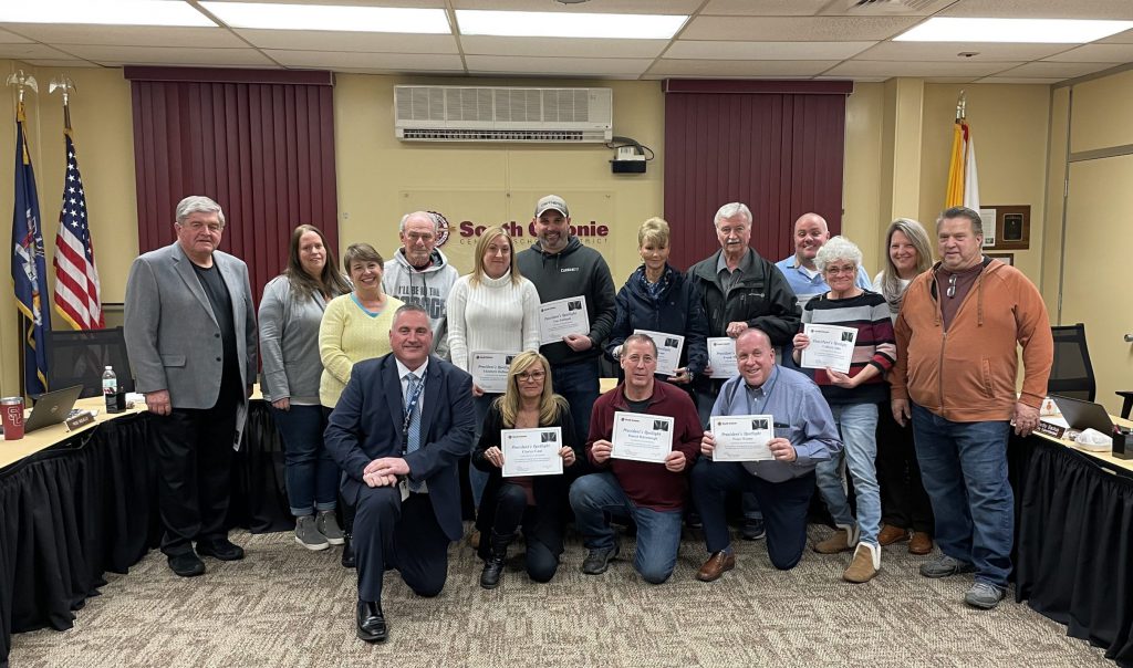 group of people posing with certificates at the board meeting