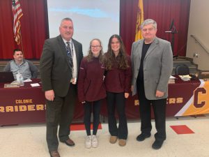 two girls posing for a photo with the Superintendent and Board President.