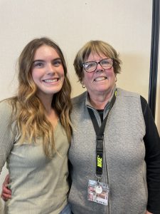 two individuals pose for a photo. Both female. One younger  ( a high school student) and one older (close to retirement).