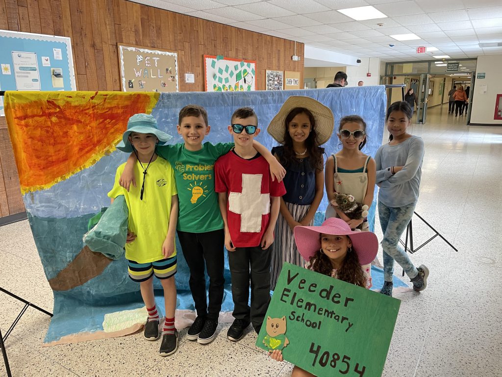 students posing for a photo with costumes on and a set behind them.