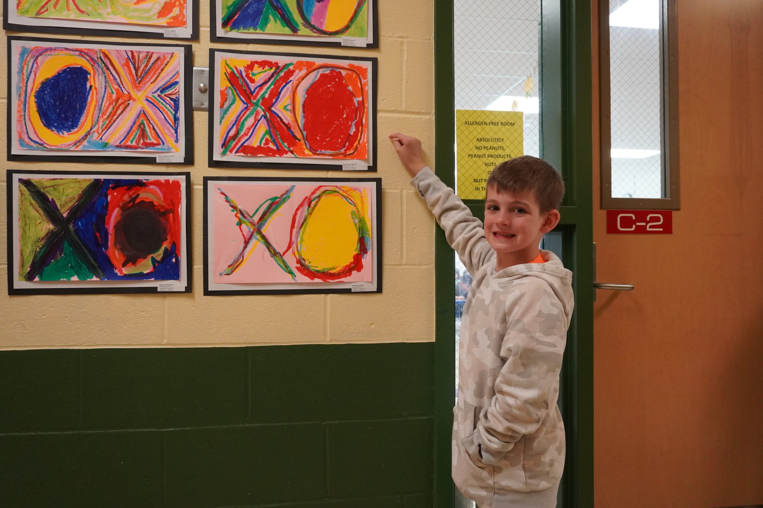 Student points to their art piece